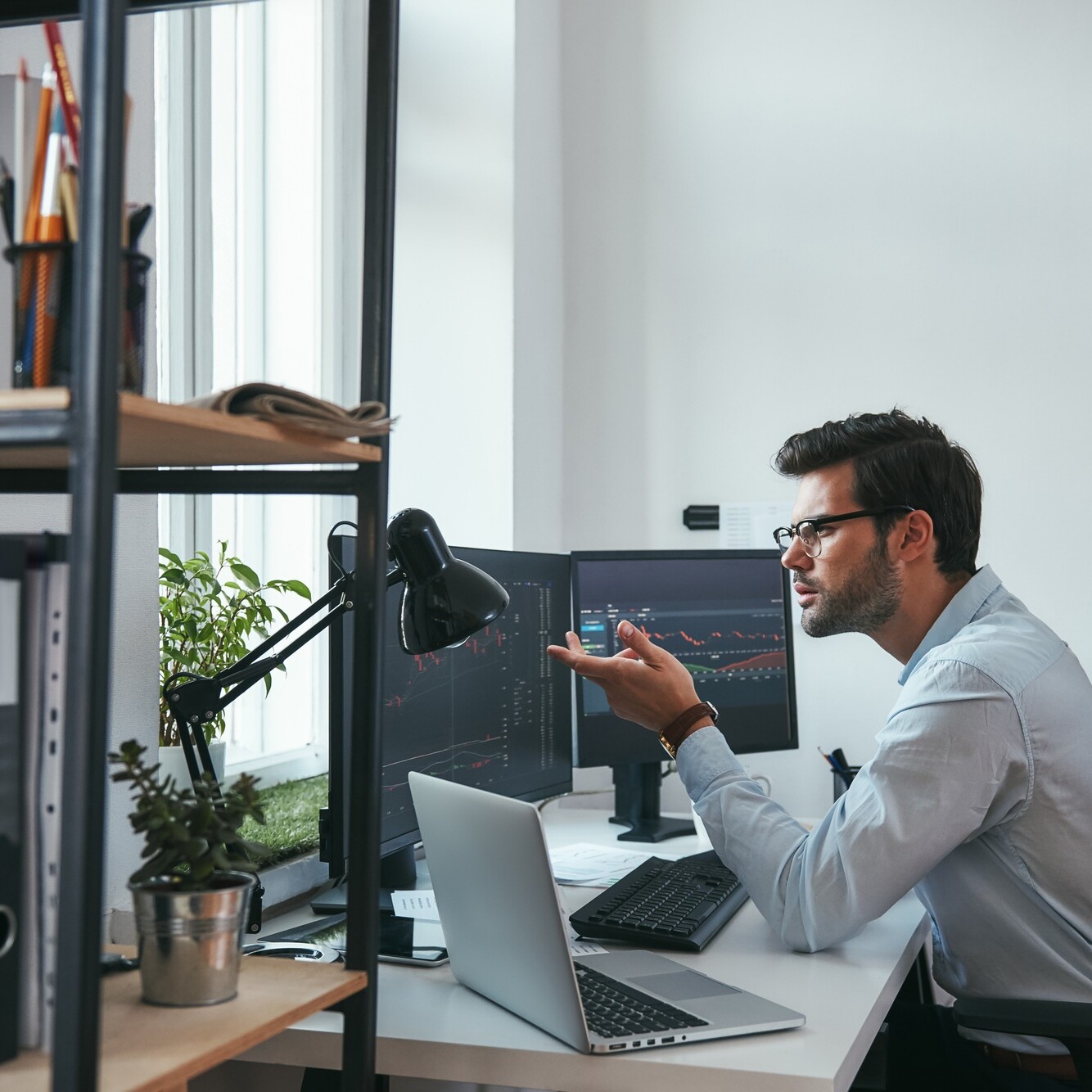 Really Side view of surprised young male stock market broker analyzing a graphs on computer and