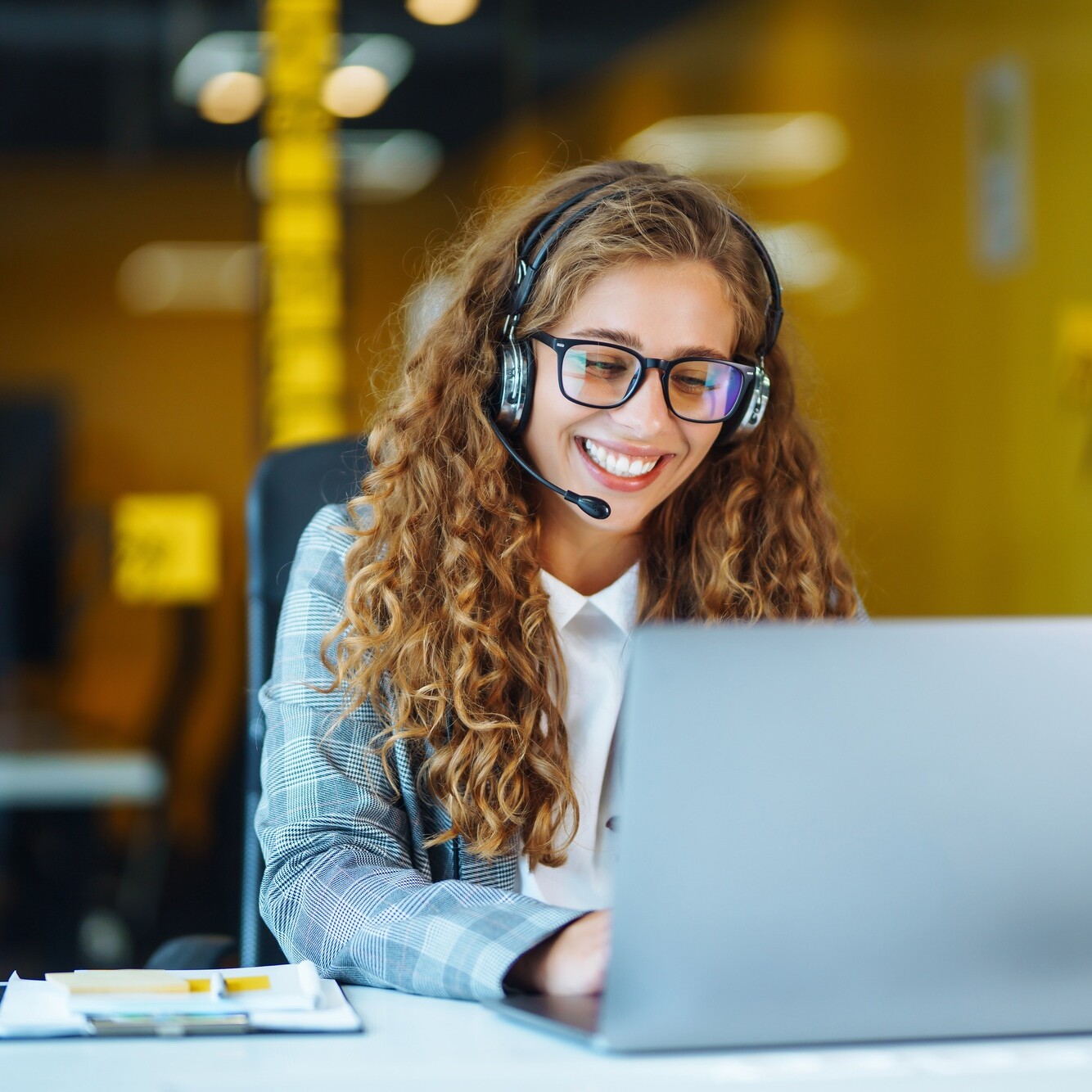 Call center agent with headset working on support hotline in modern office. Video conference.