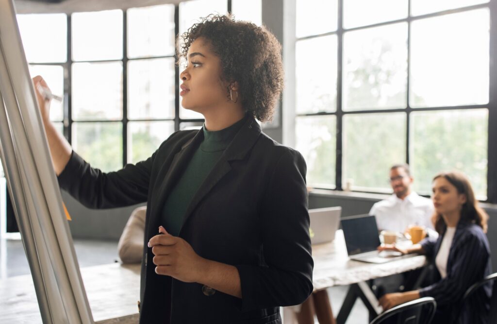Lady Writing On Whiteboard Making Presentation For Team At Office