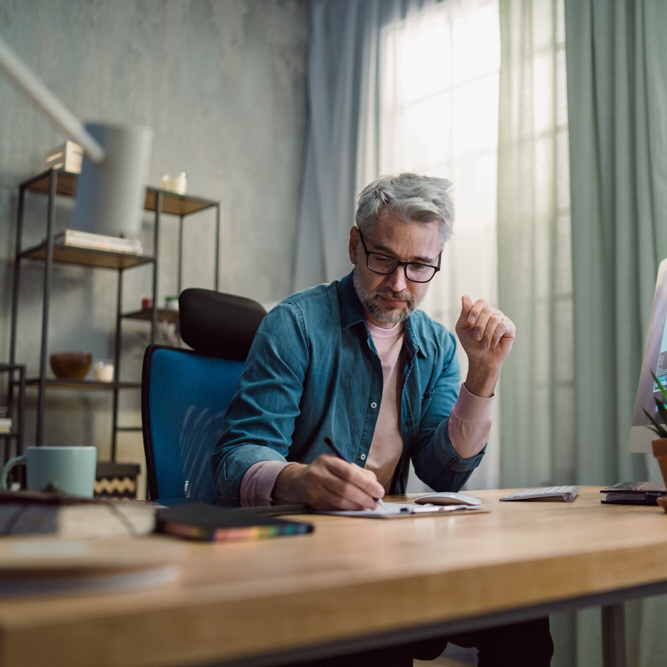 Mature man architect working on computer at desk indoors in office