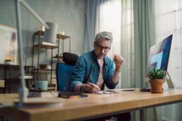 Mature man architect working on computer at desk indoors in office