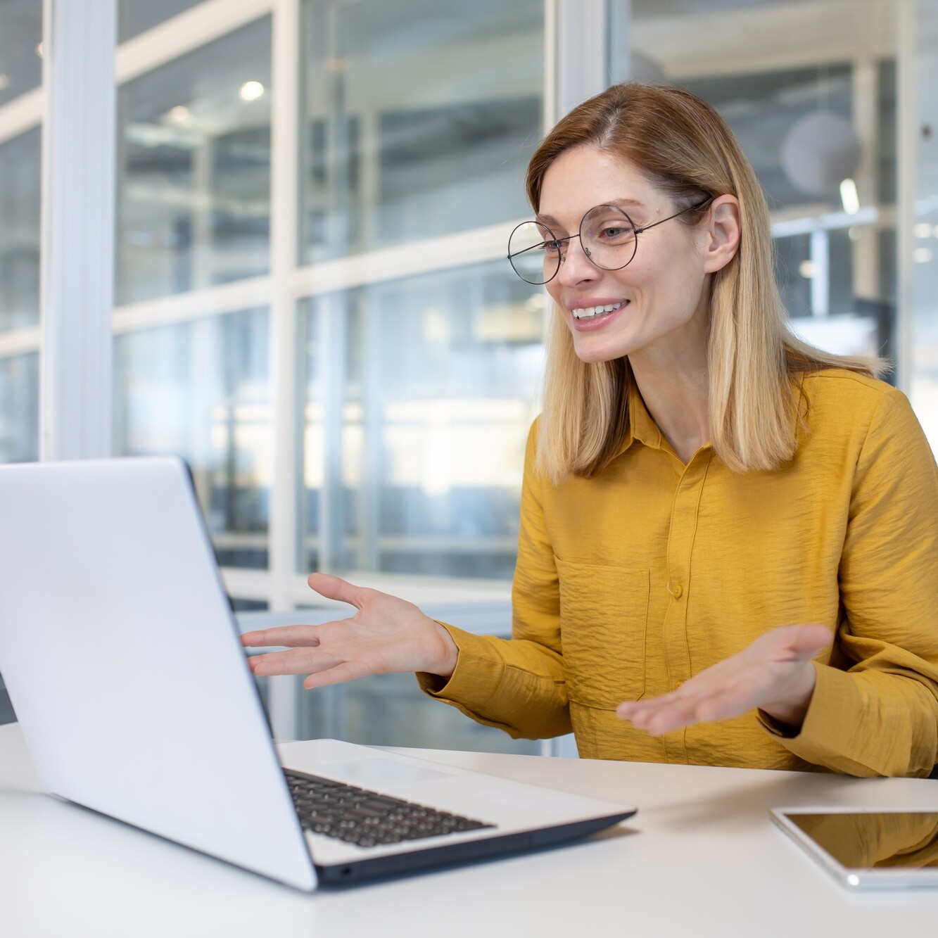 Woman in yellow blouse having a video conference call at modern office