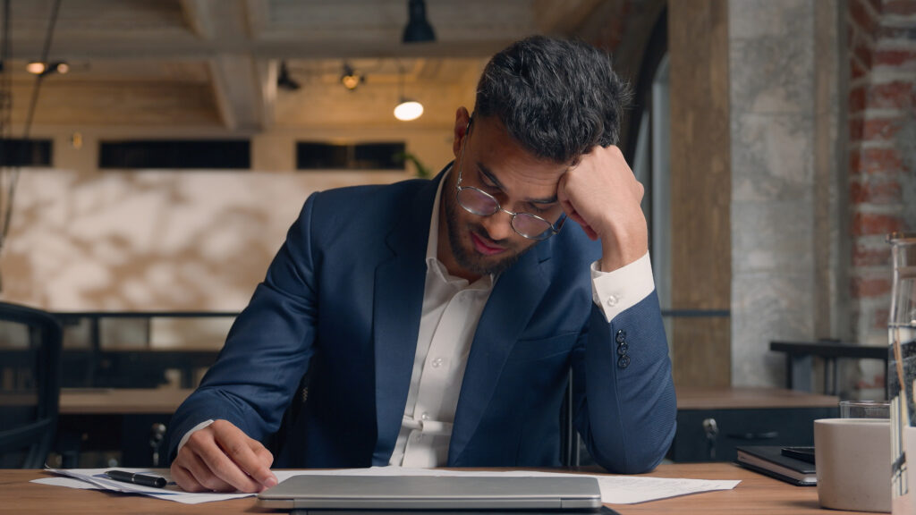 Exhausted, upset businessman looking at paperwork.
