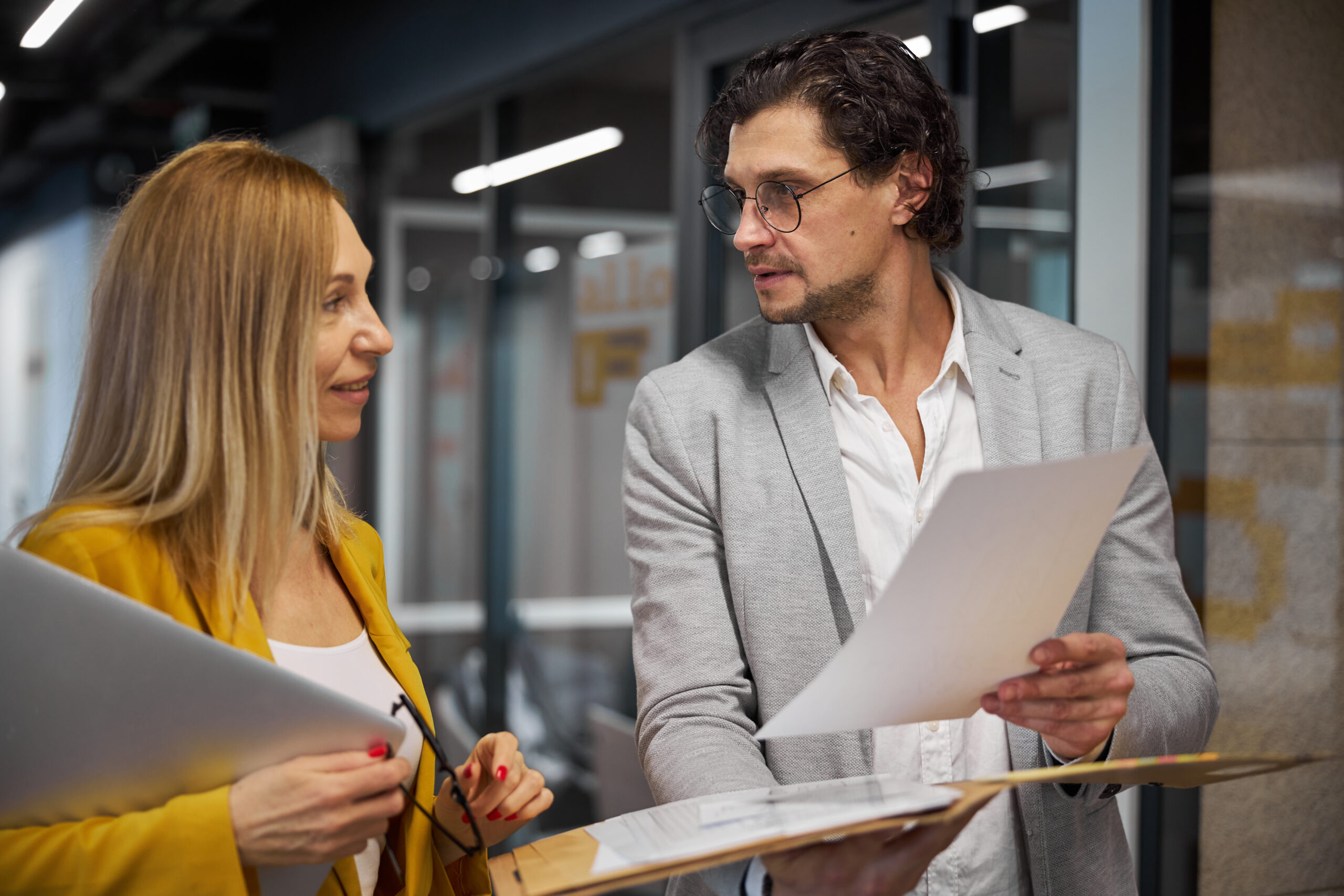 Businessman shows pleased businesswoman paperwork